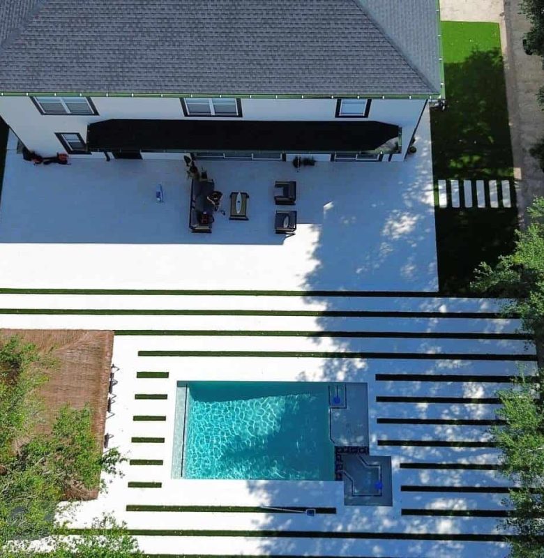 Aerial view of a modern house with a rectangular pool and striped walkway.